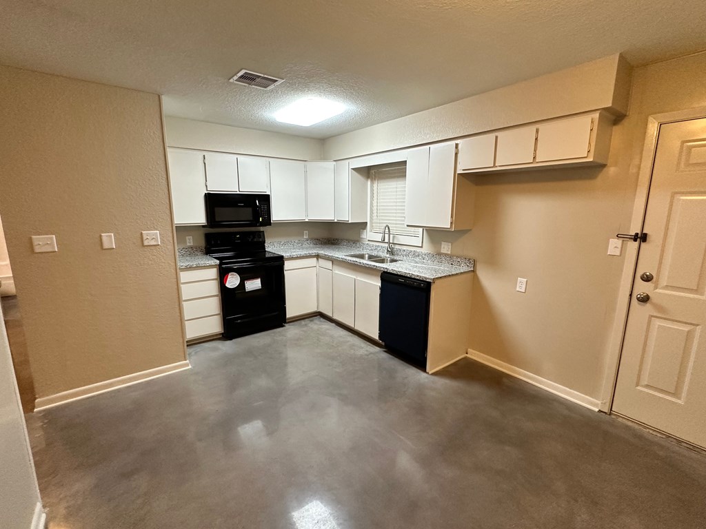 A kitchen with black appliances and white cabinets.