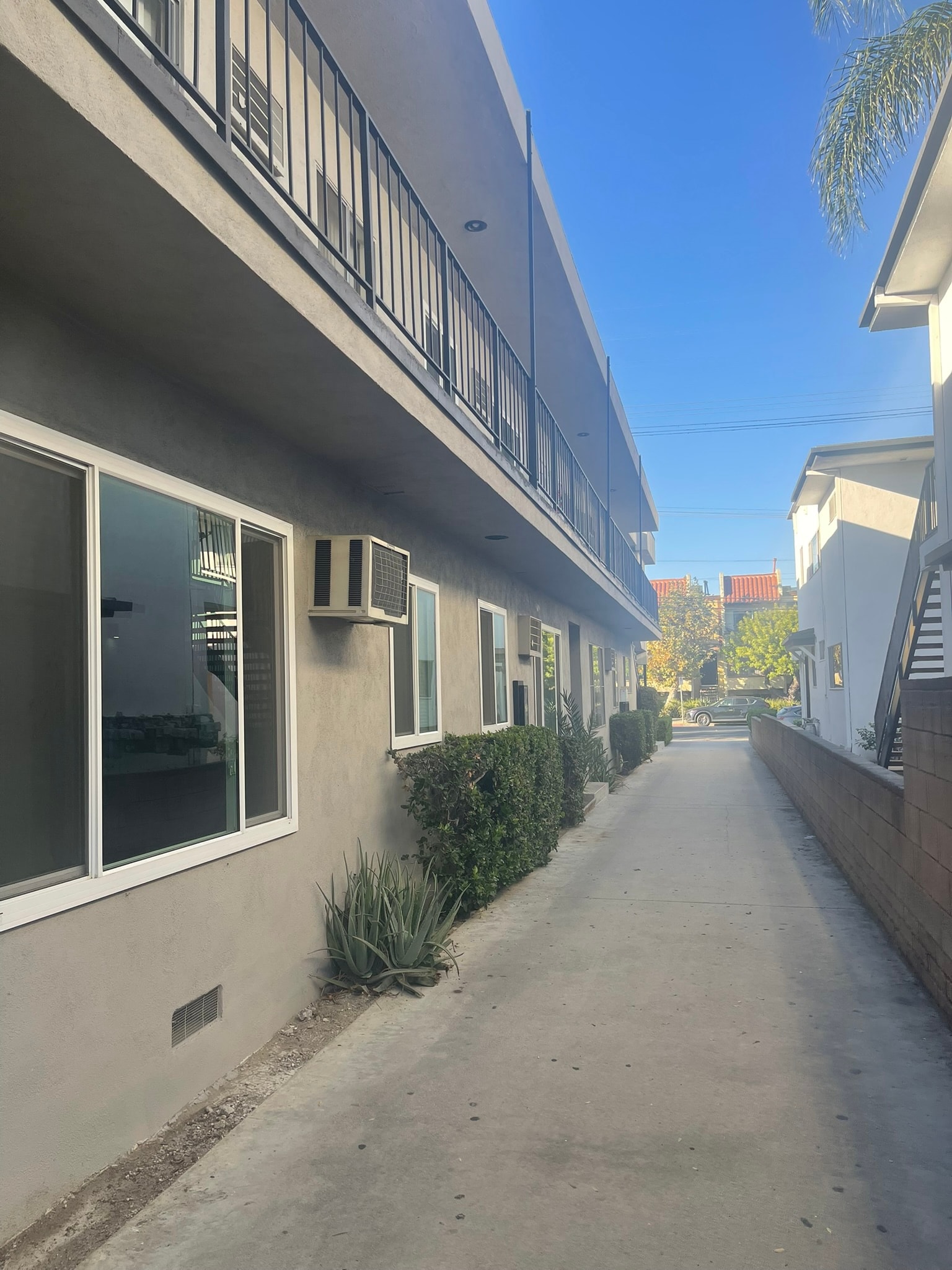 A long, narrow street with a row of houses on one side and a clear blue sky above.