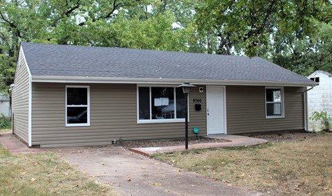A small house with a brown roof and grey siding.