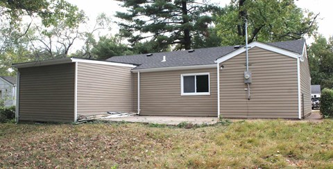 A small house with a grey roof and a brown siding.