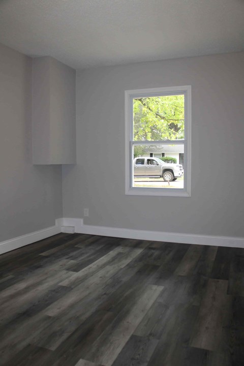 A room with a window and wooden flooring.