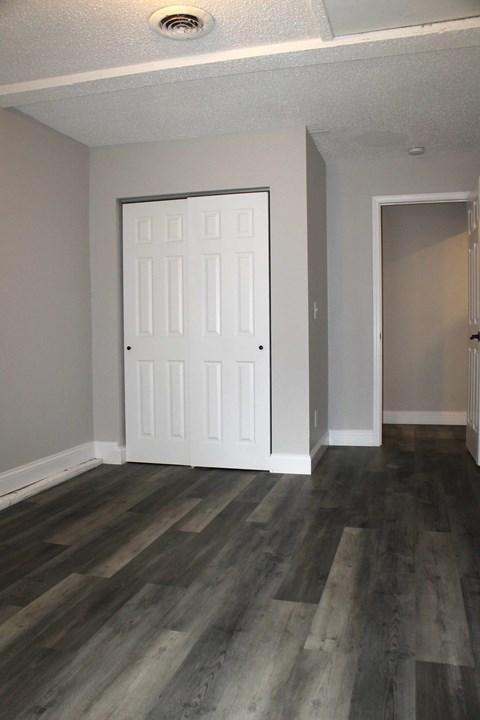 A room with a white door and wood flooring.
