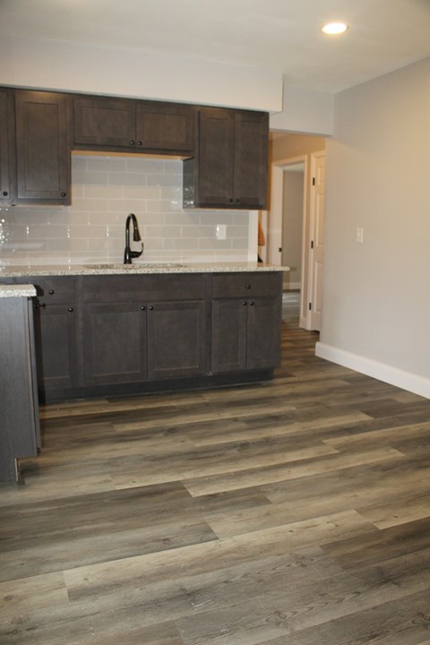A kitchen with wooden cabinets and a white backsplash.