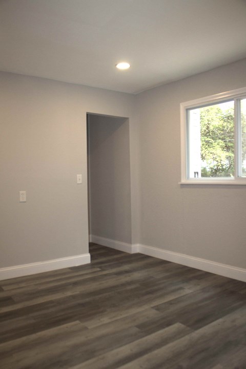 A room with a grey door and a window with a view of trees outside.