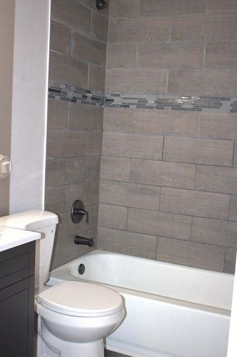 A white toilet sits next to a white bathtub in a bathroom.