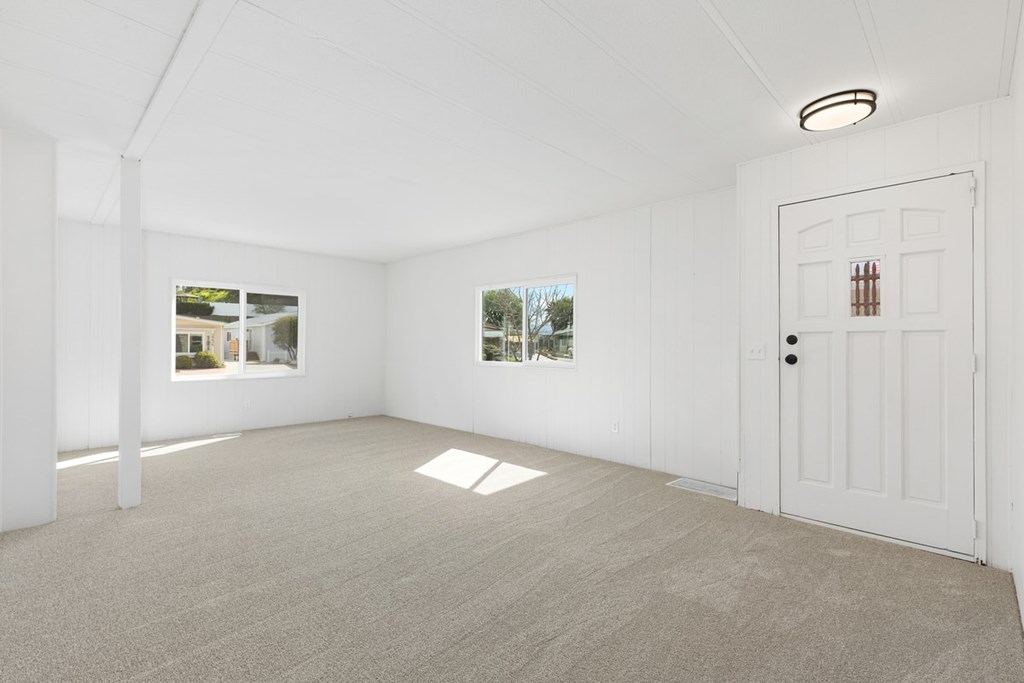 A white room with a door and two windows.