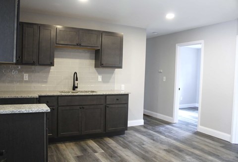 A kitchen with dark wood cabinets and a granite countertop.