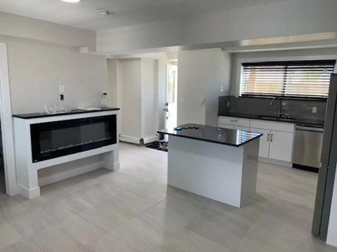 A modern kitchen with a black countertop and white cabinets.