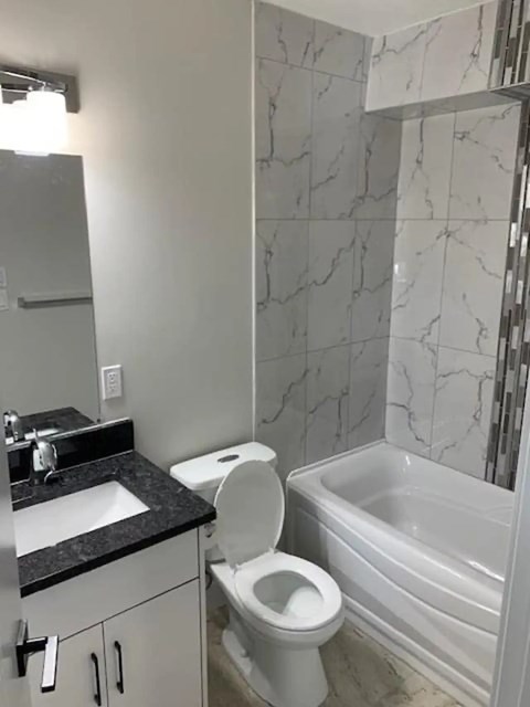 A white toilet sits in a bathroom with marble tile walls.