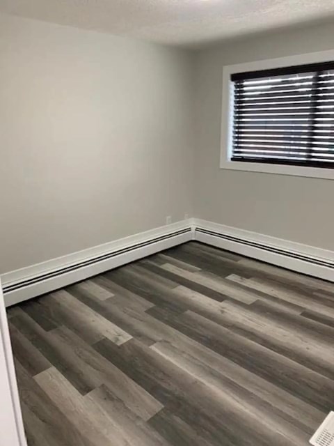 A room with a wooden floor and a window with blinds.