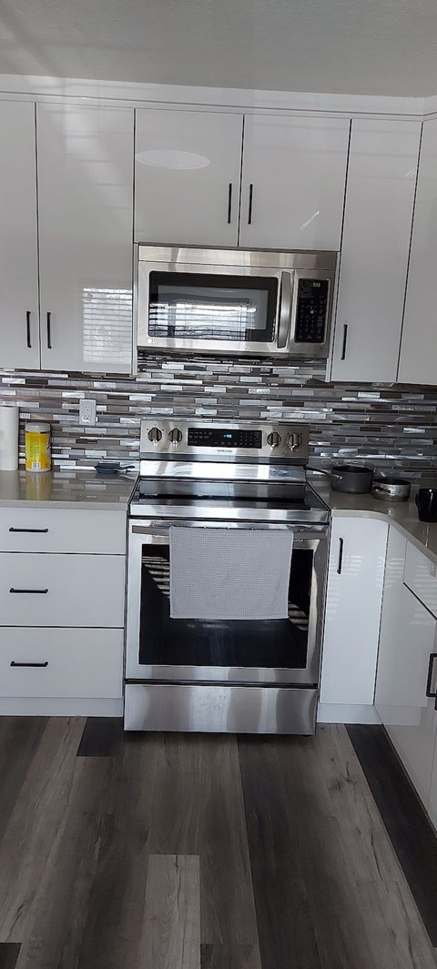 A modern kitchen with a stainless steel oven and white cabinets.