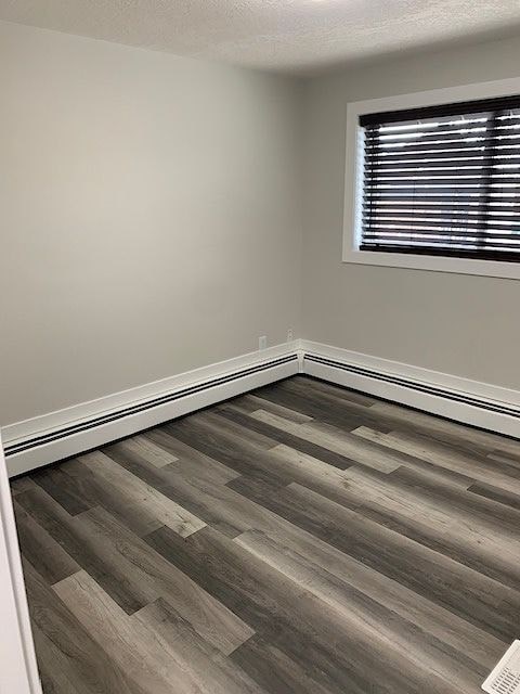 A room with a wooden floor and a window with blinds.