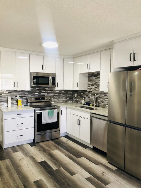 A modern kitchen with white cabinets and stainless steel appliances.