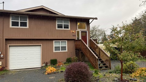 A house with a brown siding and a white garage door.