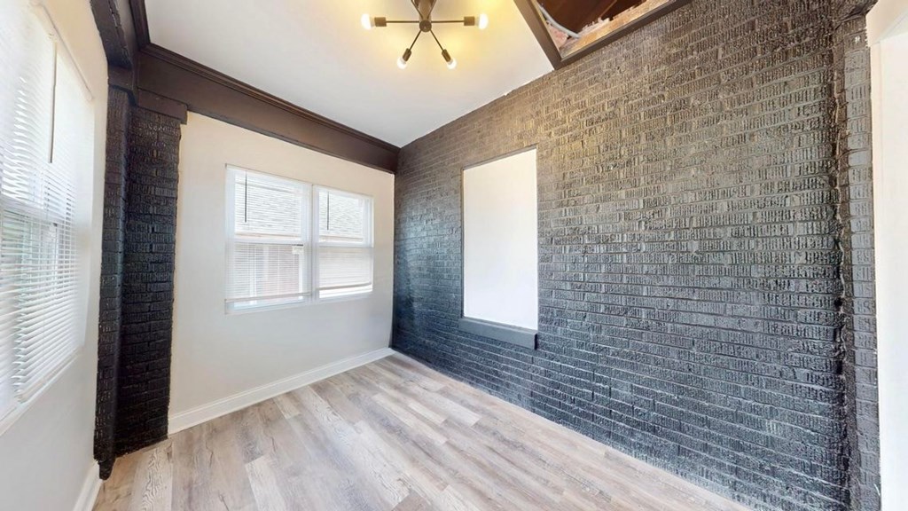 A room with a brick wall and wooden flooring.