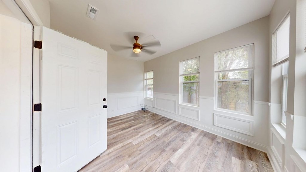 A room with a white door and a ceiling fan.
