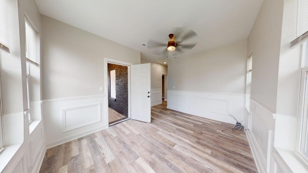 A room with a ceiling fan and wooden flooring.