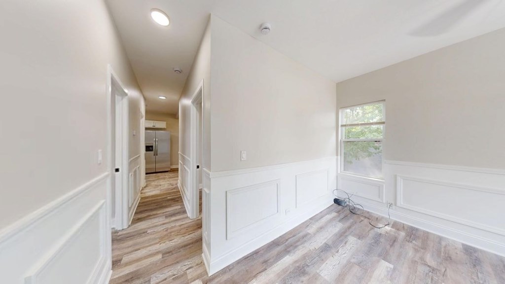 A long, narrow hallway with wood flooring and white walls.