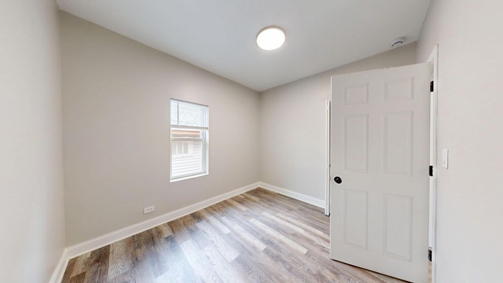 A room with a white door and a window with blinds.