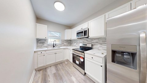 A kitchen with a refrigerator, microwave, and oven.
