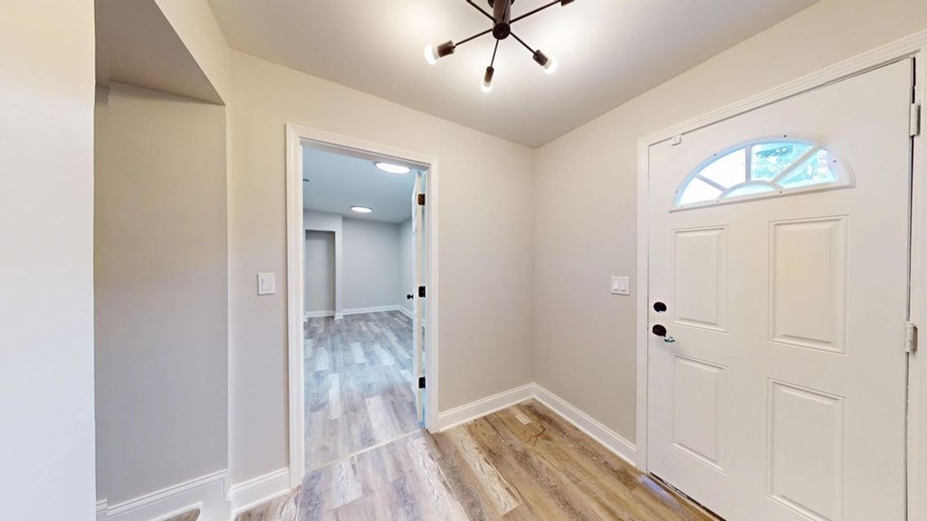 A room with a white door and a window with a stained glass design.