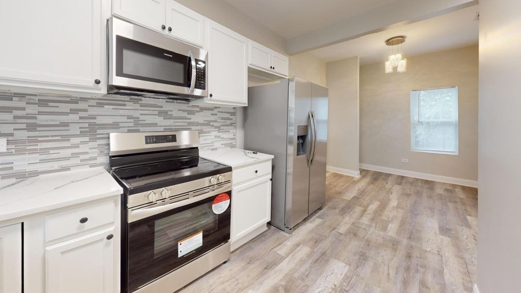 A kitchen with a stove, oven, refrigerator, and microwave.