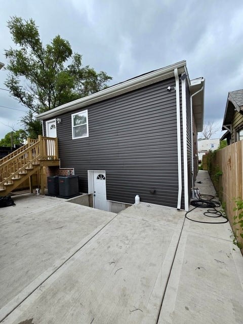 A grey garage with a white door and a brown staircase.