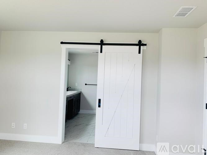 A white door with a black handle is open to a bathroom.
