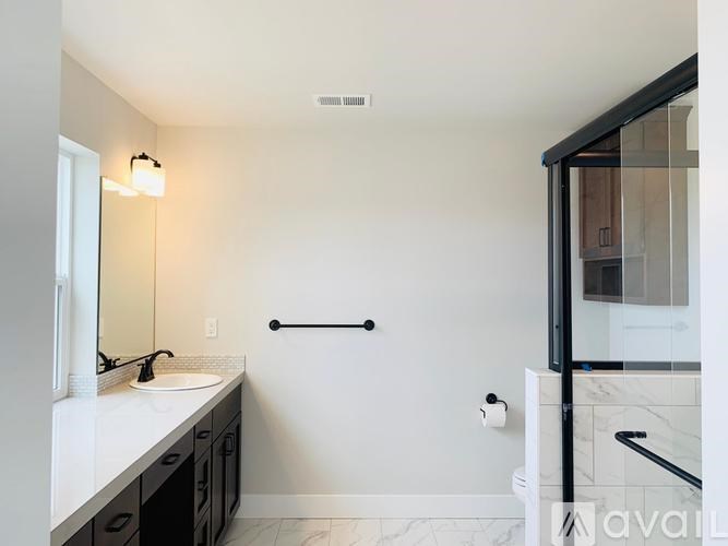 A bathroom with a sink, mirror, and a glass shower door.