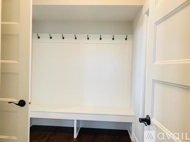 A white closet with a bench and hooks for hanging clothes.