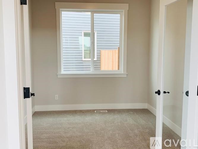 A room with a window covered by white blinds.