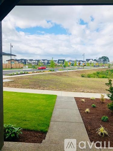 A view from a window of a green lawn and a red car in the distance.