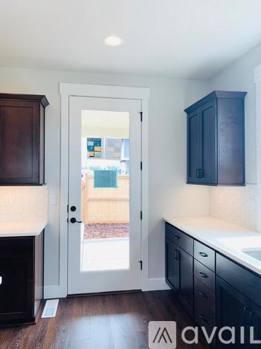 A kitchen with a white counter top and dark wood cabinets.