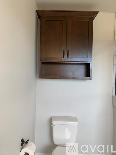 A white toilet with a roll of toilet paper on top of it.