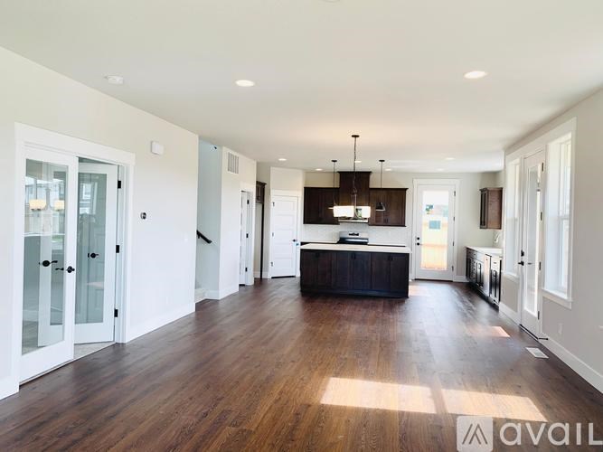 A spacious kitchen with wooden floors and white walls.