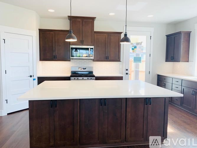 A kitchen with a white island and dark brown cabinets.
