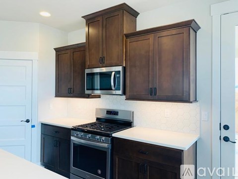 A kitchen with dark brown cabinets and a white countertop.