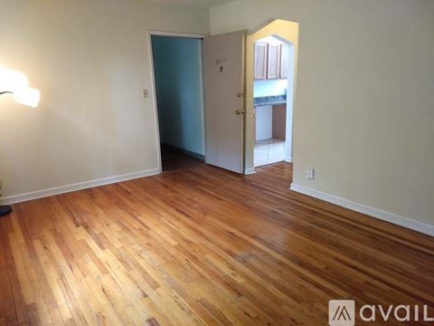 A room with wooden flooring and two doors, one of which is open.