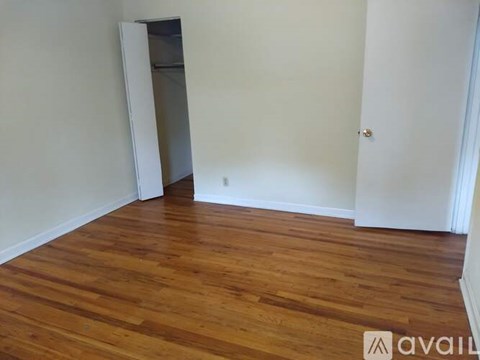 A room with wooden flooring and a white wall with a door.