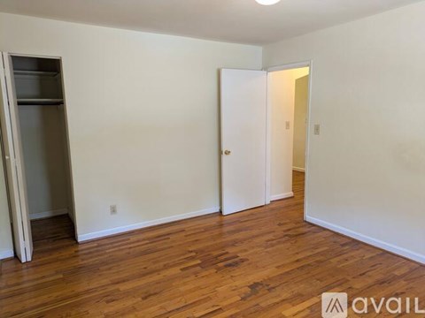 A room with wooden floors and two doors, one of which is open.