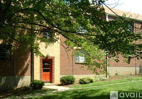 A red door is on the left side of a brick building.