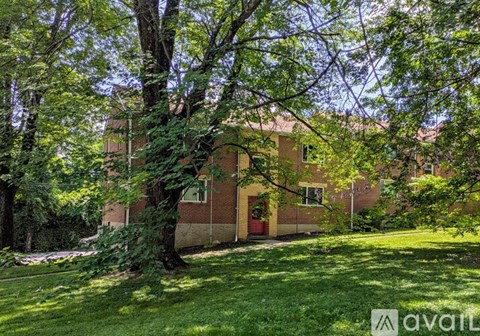 A tree in front of a building with a red door.
