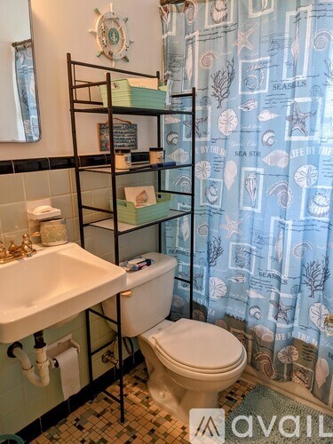 A bathroom with a toilet, sink, and shower curtain.