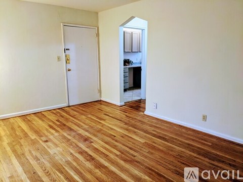 A room with wooden flooring and a door leading to a kitchen.