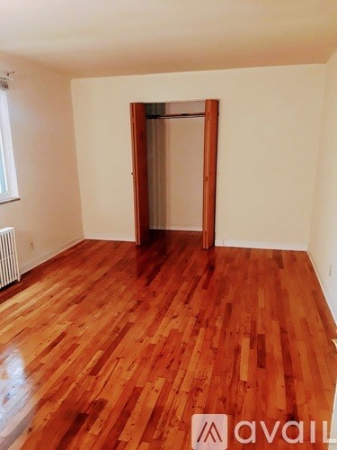 A room with wooden flooring and a doorway leading to another room.
