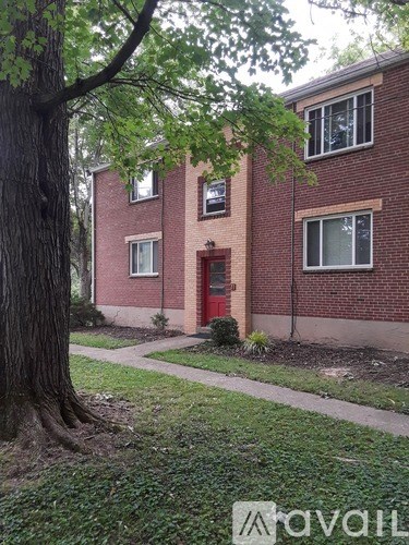 A red brick house with a tree in front.