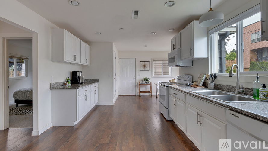A kitchen with white cabinets and a wooden floor.