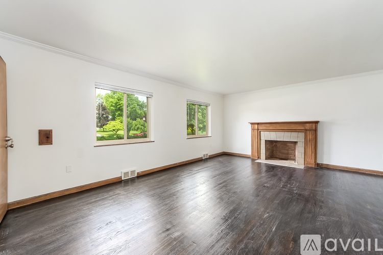 A spacious room with a fireplace and wood flooring.