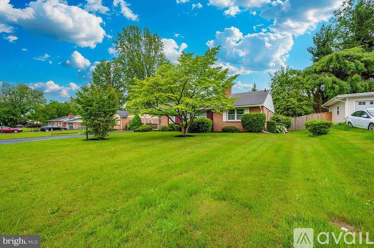 A bright, sunny day in a suburban neighborhood with a house and a car parked in the driveway.