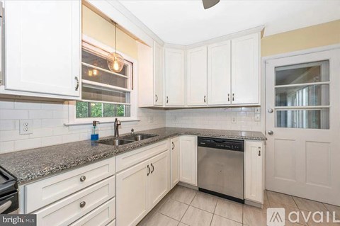 A kitchen with white cabinets and a granite countertop.